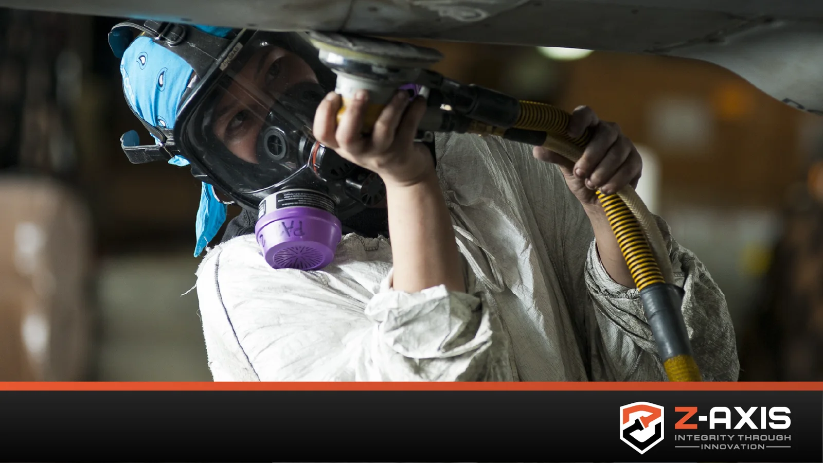 person wearing facemask grinding underside of some equipment